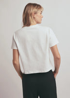 Person wearing a white t-shirt and black pants on a plain background