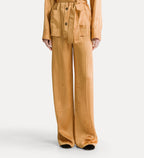 A model is shown from the waist down wearing a matching mustard yellow two-piece set consisting of a belted cropped jacket and wide-leg trousers, with a subtle vertical textured stripe pattern.