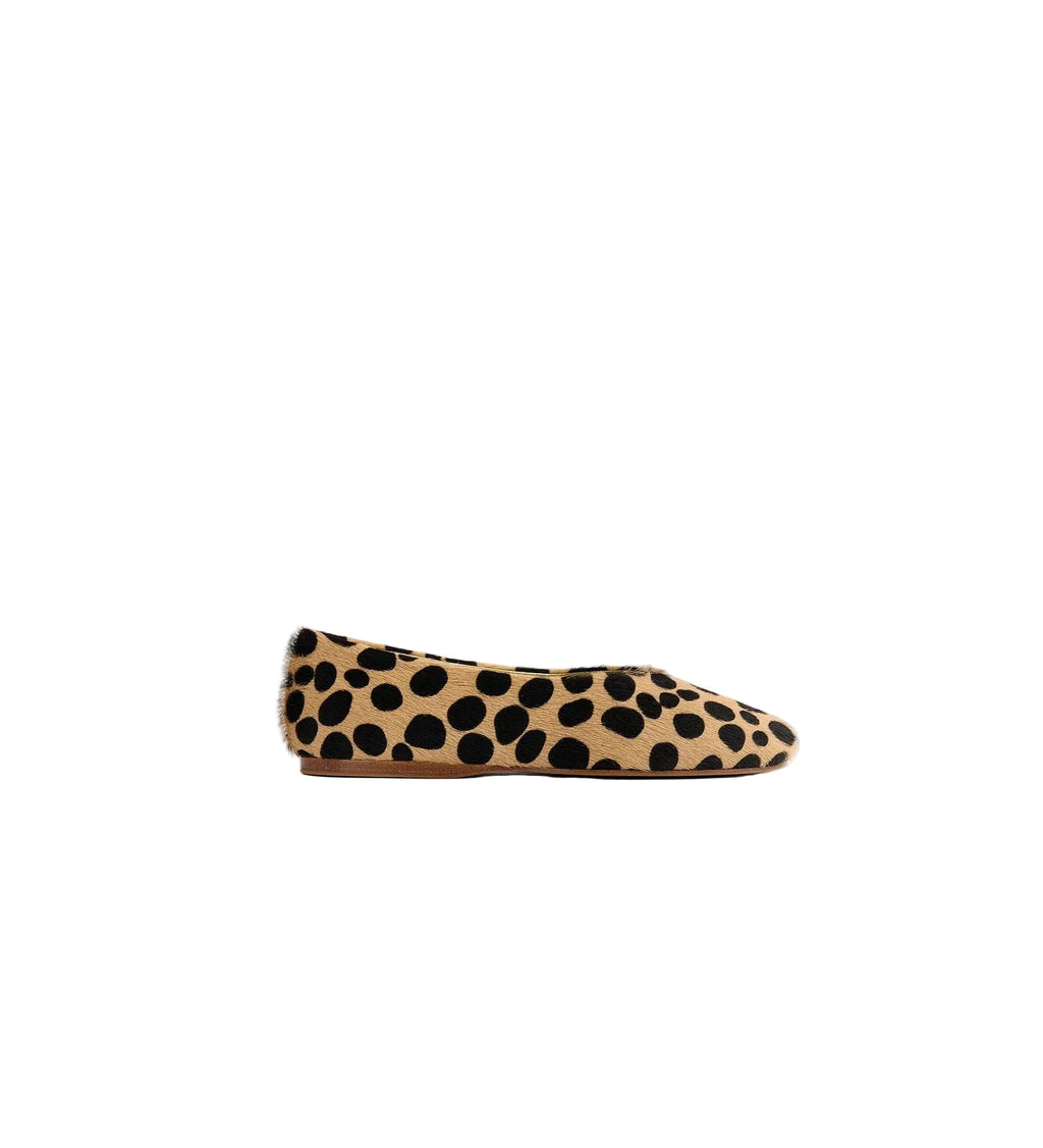 A single flat shoe in tan suede with a black leopard print pattern, shown in a side profile against a light gray background.