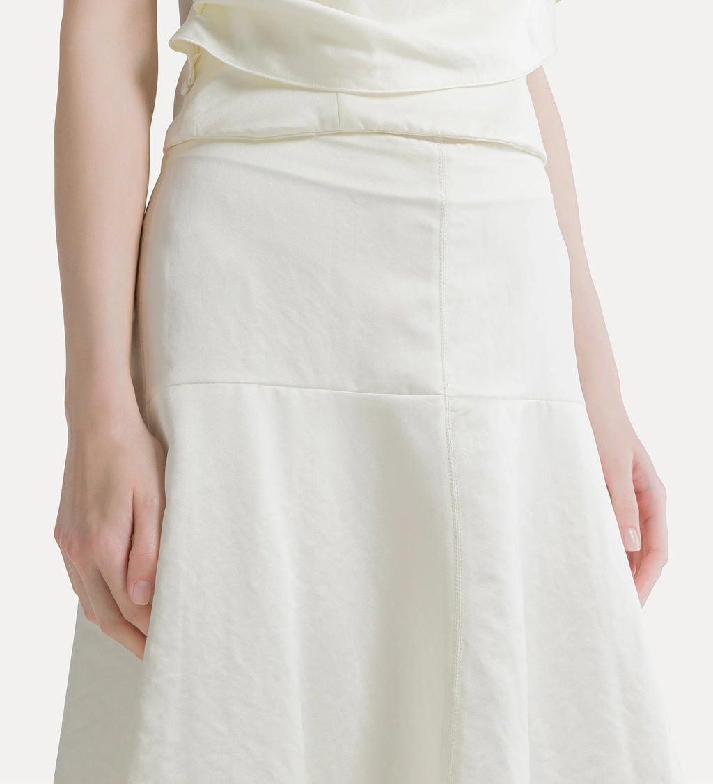 Close-up of a model wearing a cream-colored high-waisted skirt with a gathered waistband and a subtle A-line silhouette.