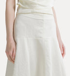 Close-up of a model wearing a cream-colored high-waisted skirt with a gathered waistband and a subtle A-line silhouette.