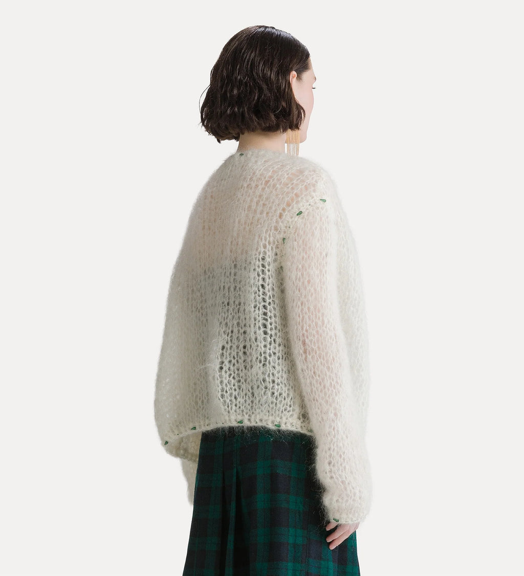 A model shown from the back wearing a fuzzy, open-knit cream-colored sweater and a green plaid skirt, set against a plain light gray studio background.