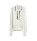 An off-white knit polo sweater with black embroidered vertical details down the center front and a black-trimmed collar, shown against a light gray background.