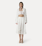 A model wearing a white long skirt with floral applique details and a matching top.