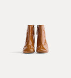 Pair of brown patent leather ankle boots on a white background