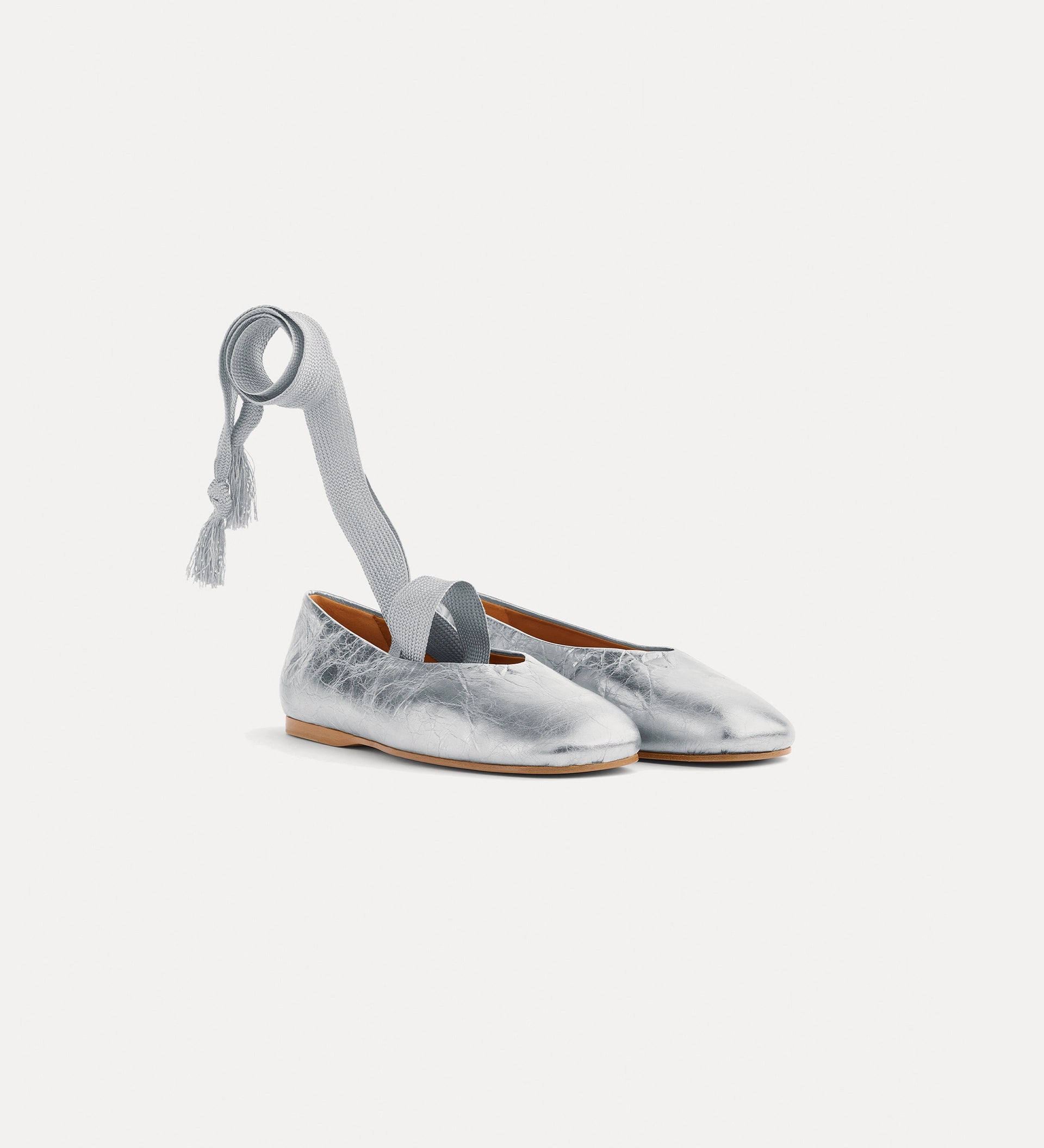 Silver metallic shoes with a ribbon on a white background