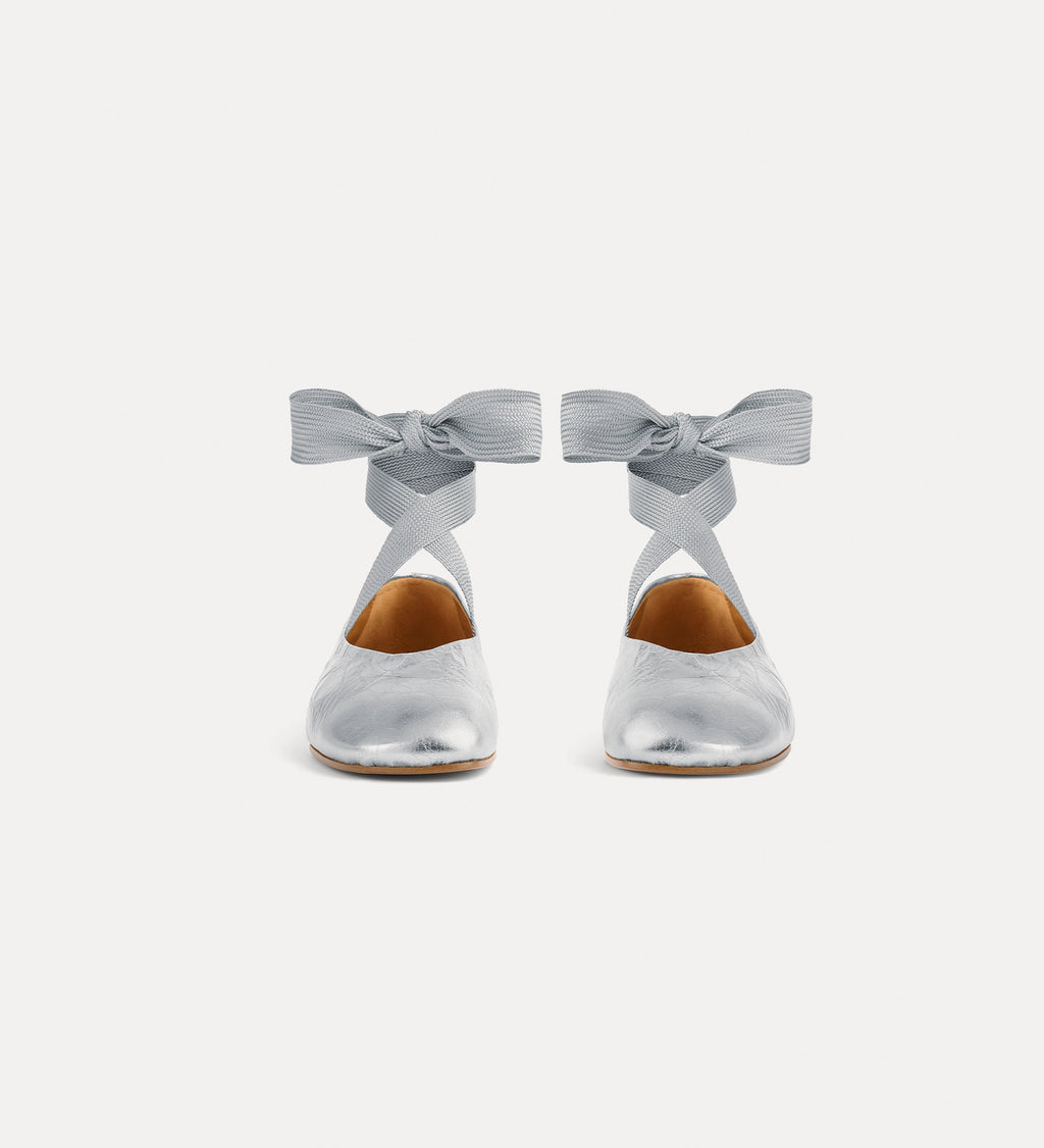 Silver shoes with bow details on a white background