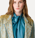 Woman wearing a patterned jacket over a blue blouse with a plain background