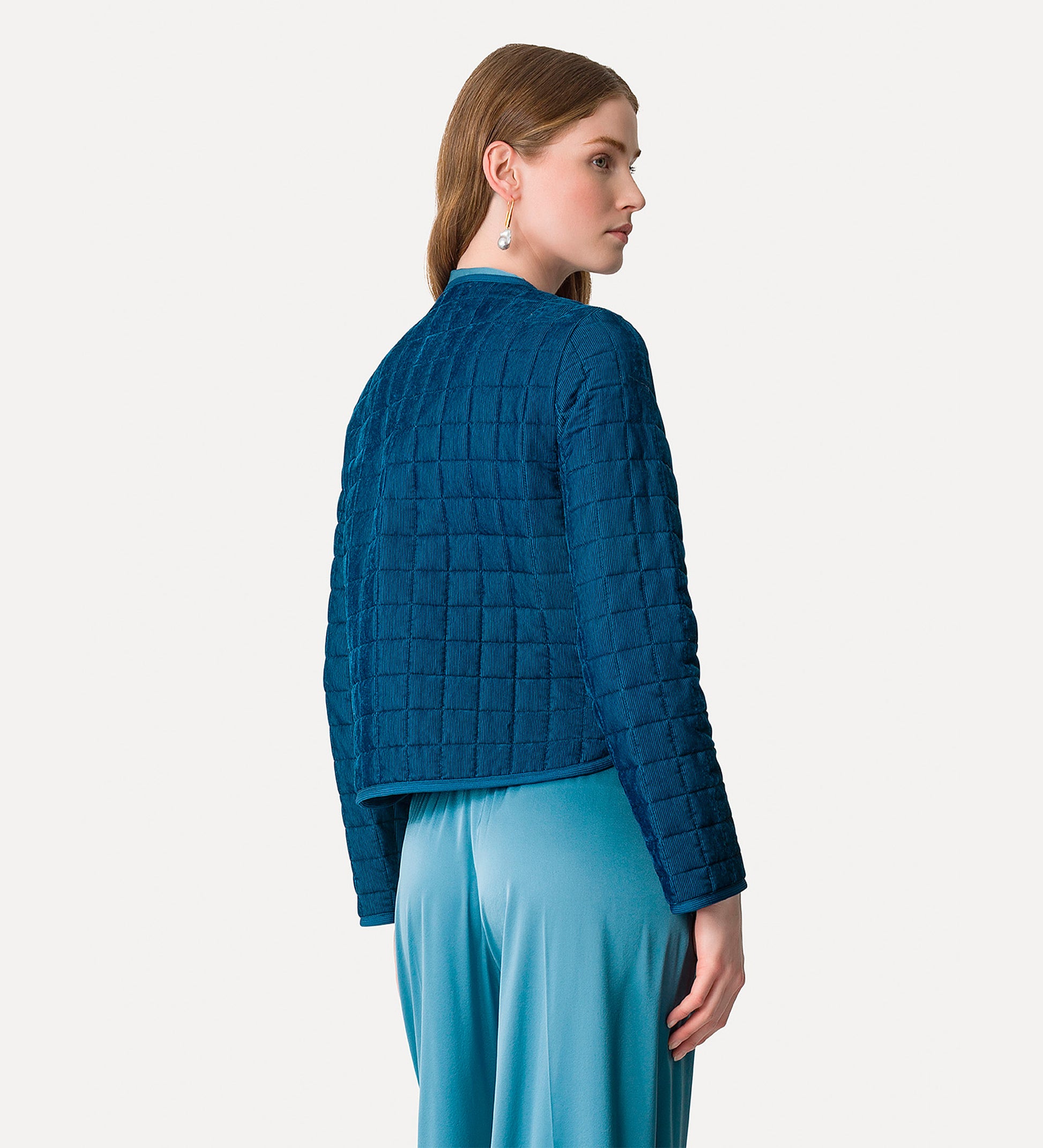 Woman wearing a blue textured jacket and pants on a white background