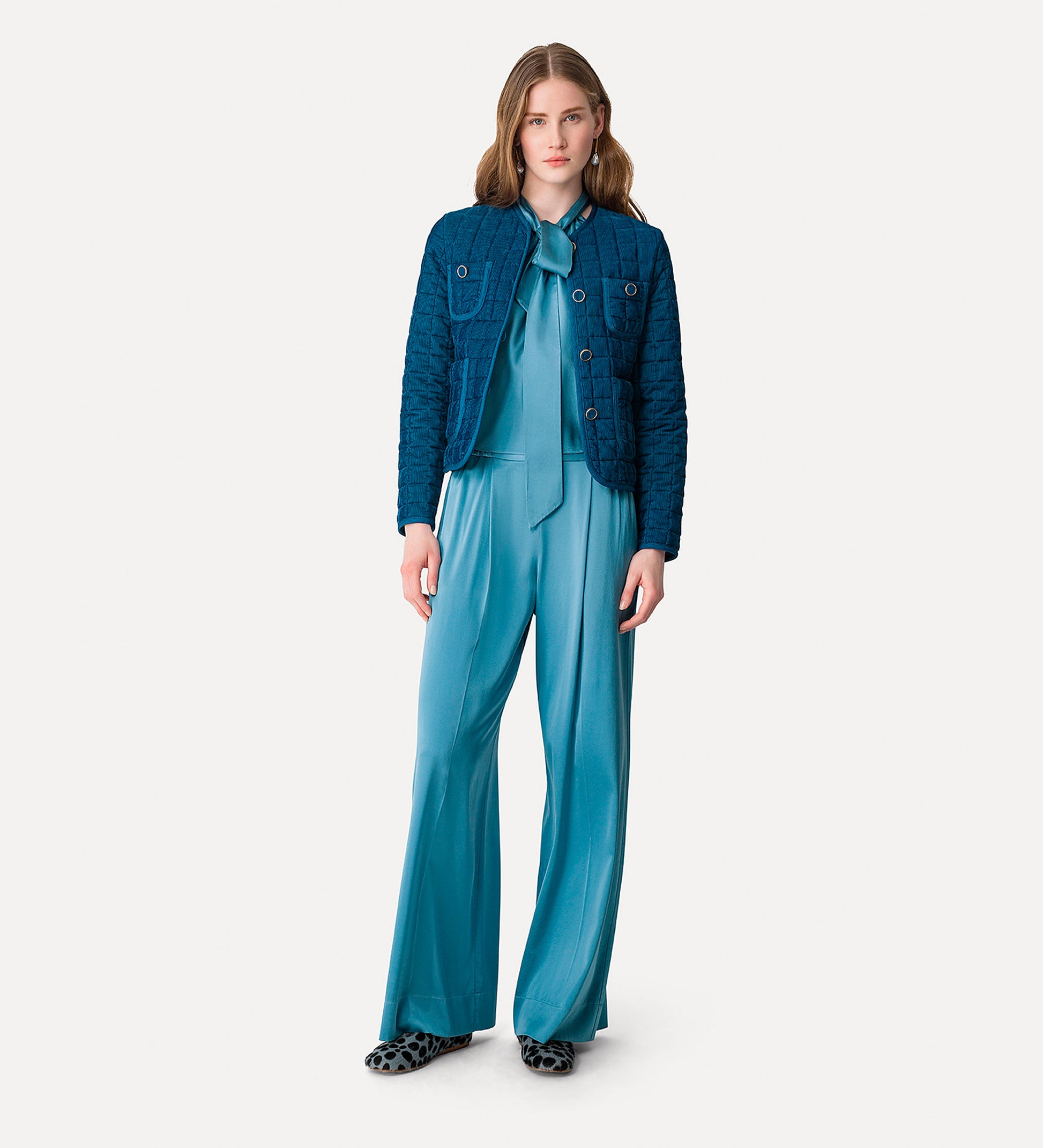 Woman wearing a blue outfit with a jacket and pants on a white background