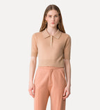 Woman wearing a beige polo shirt and peach pants on a white background