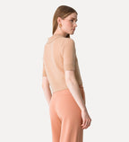 Woman wearing a beige top and peach pants on a white background