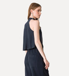 Woman wearing a navy blue sleeveless top and pants on a white background