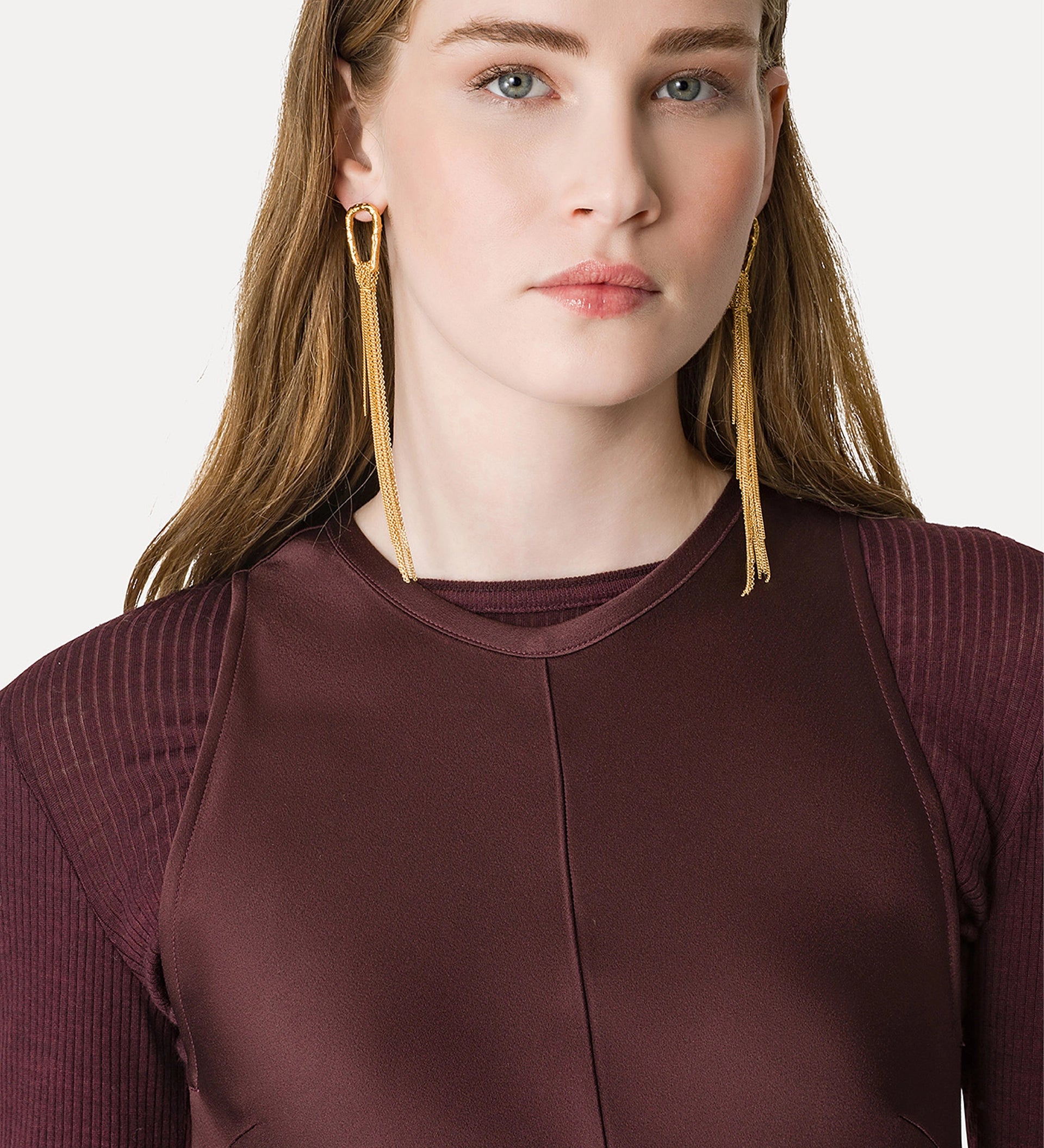 Woman wearing gold hoop earrings with a plain background