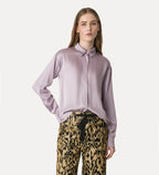 Woman wearing a light purple blouse and leopard print pants on a white background