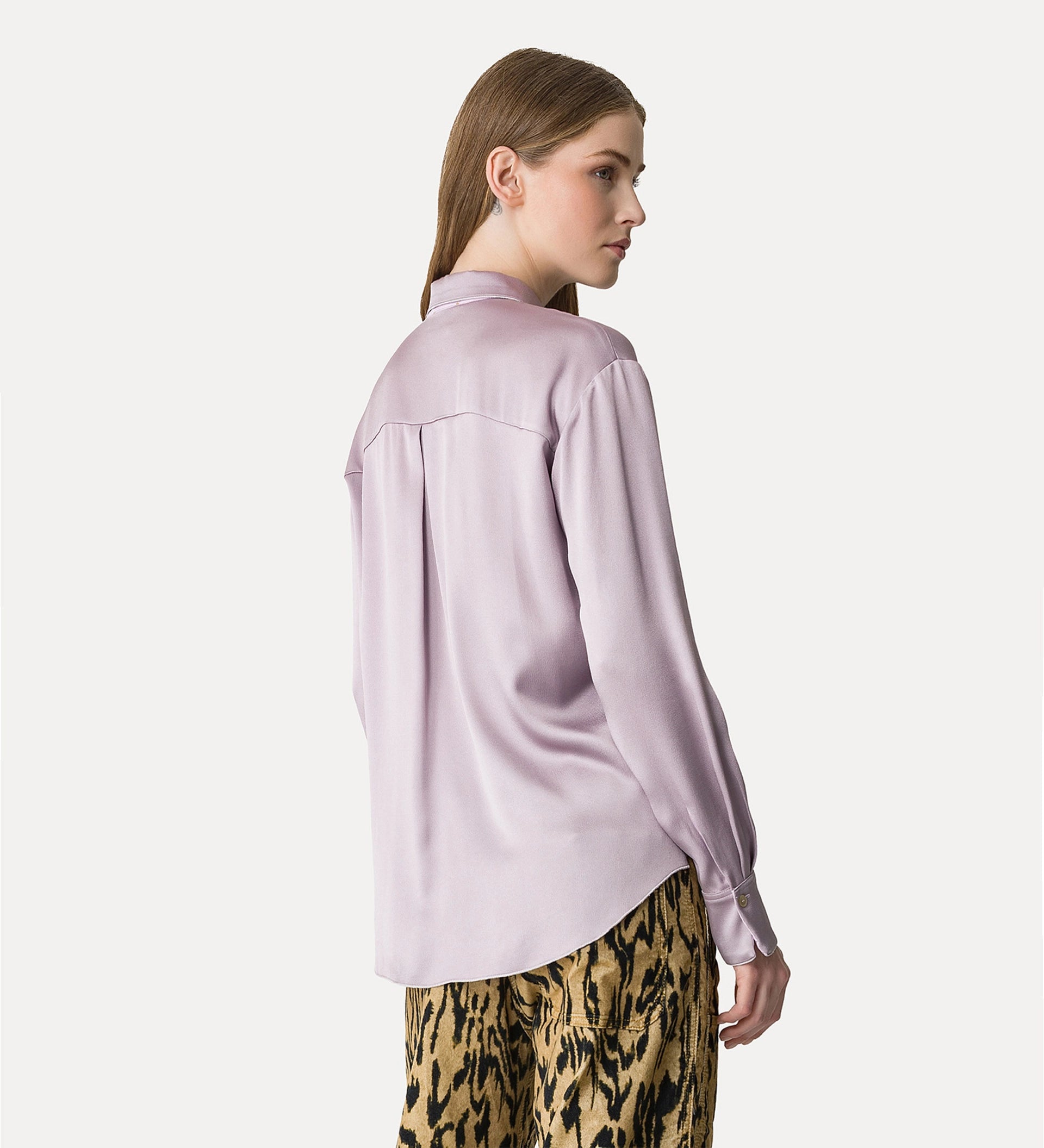Woman wearing a light purple blouse and leopard print pants on a white background