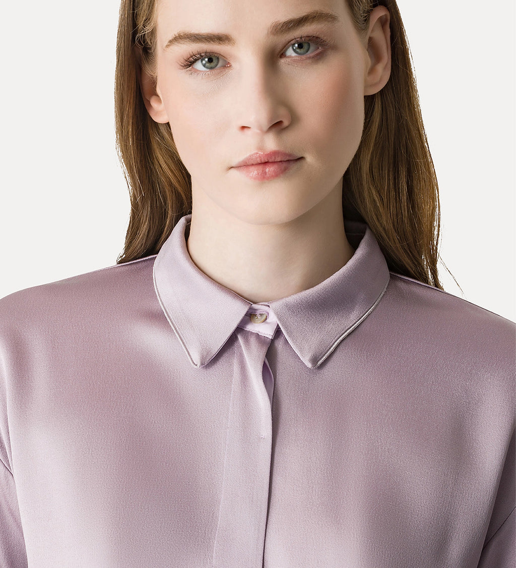 Woman wearing a light purple blouse with a collar against a white background