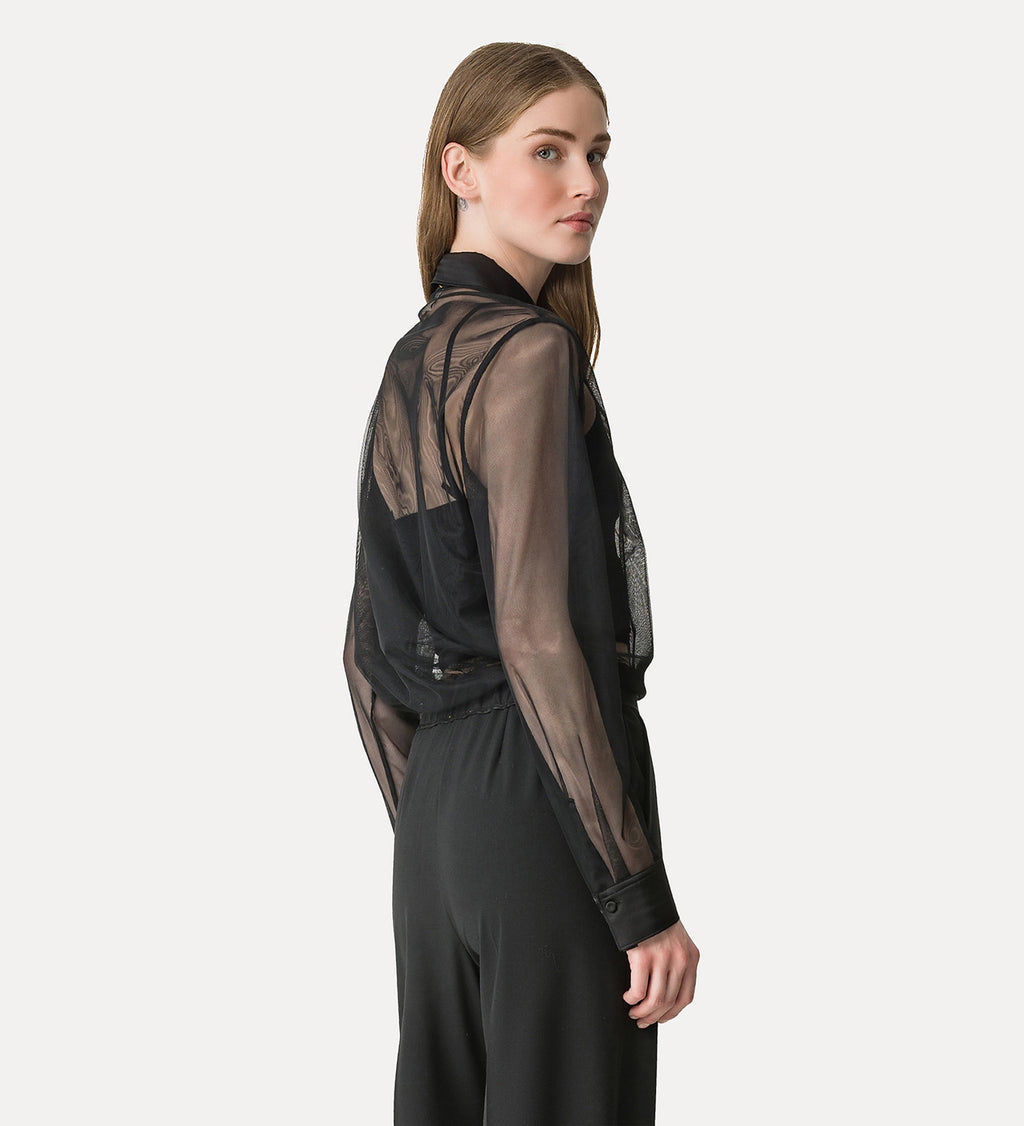 Woman wearing a black sheer blouse over a black outfit on a white background