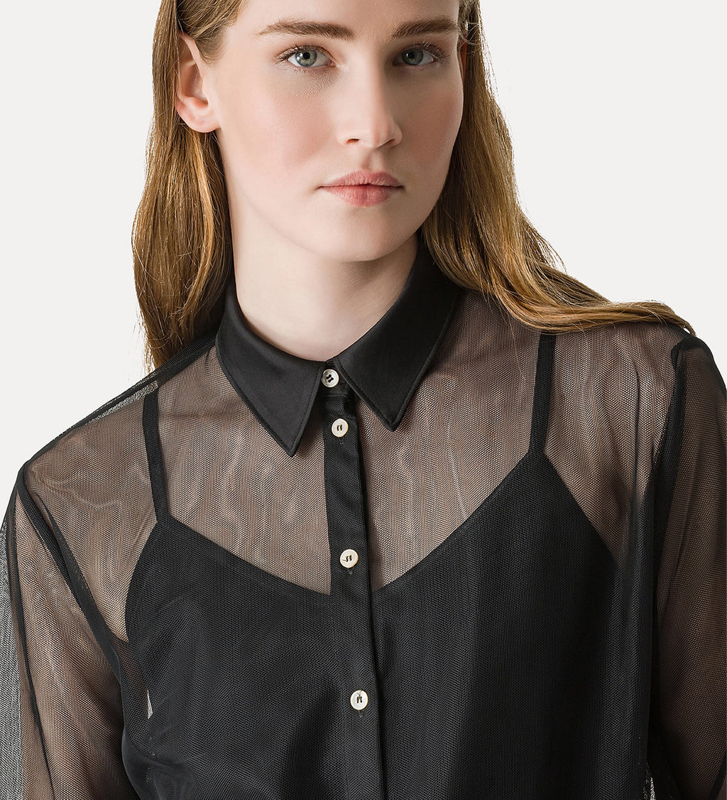 Woman wearing a black and sheer blouse with a plain background