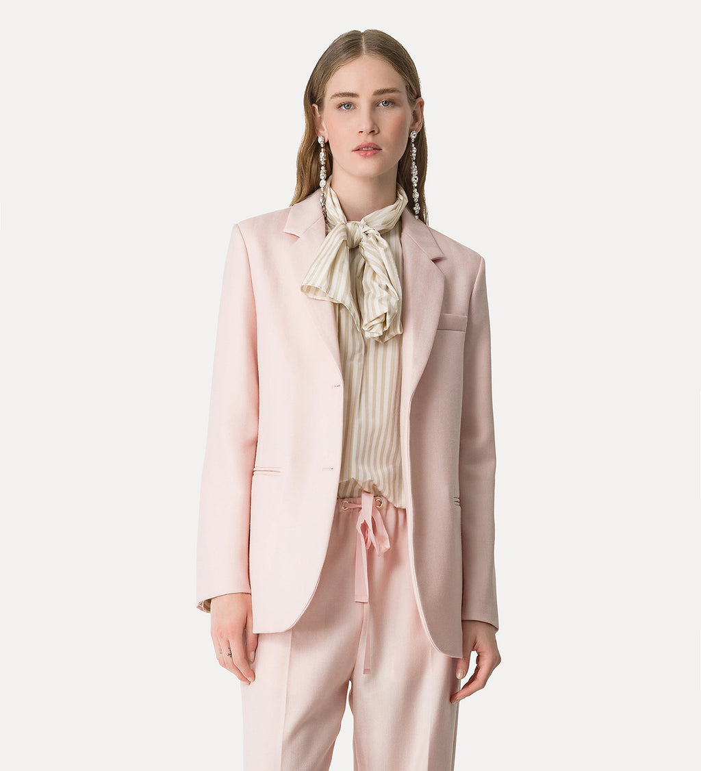 Woman wearing a light pink suit with a white blouse on a white background