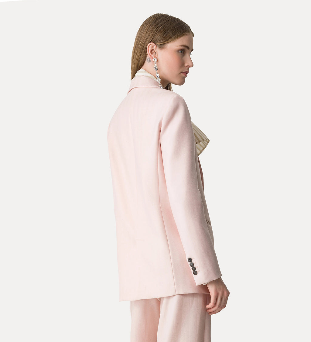 Woman wearing a light pink blazer with a white background