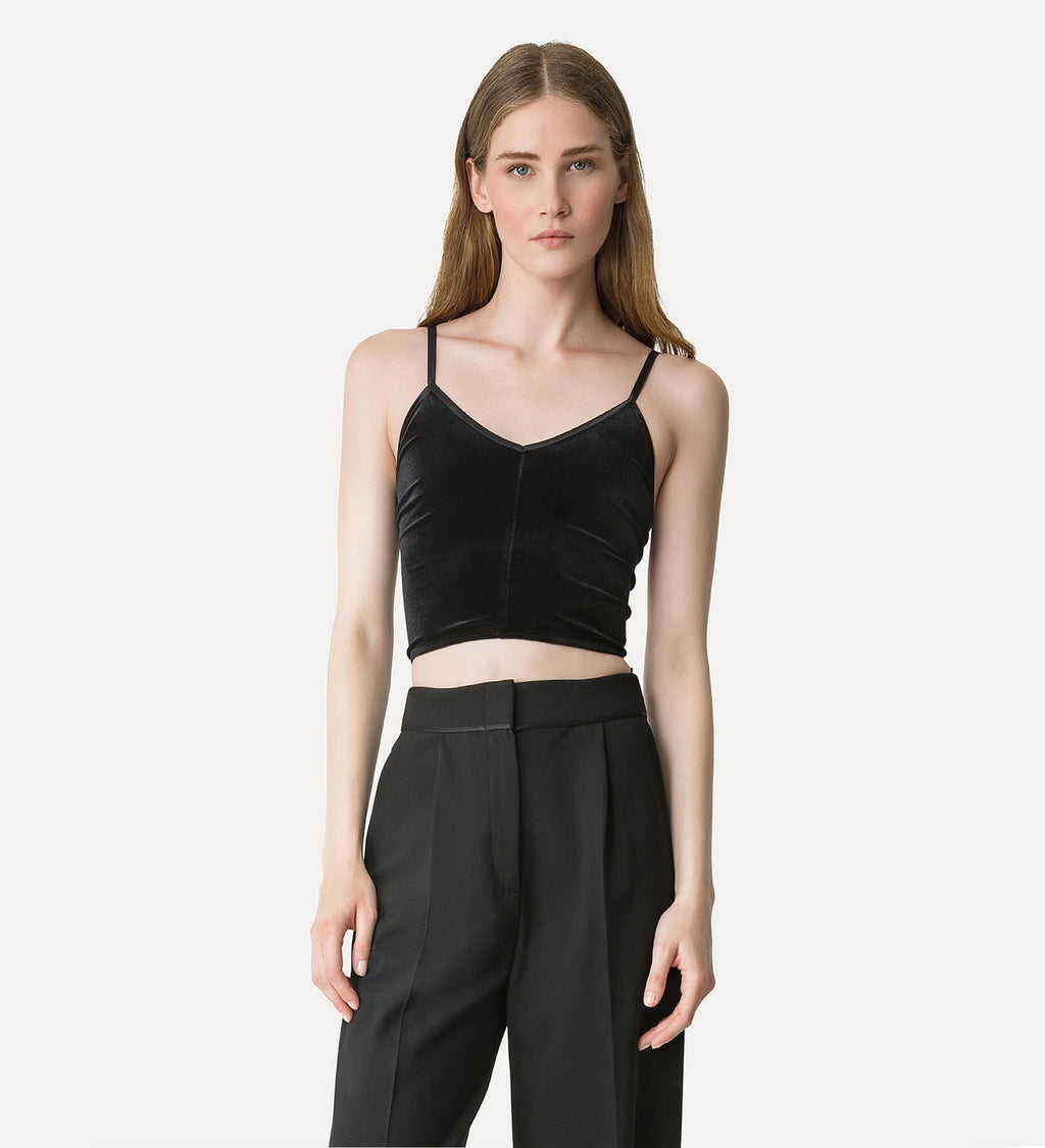 Woman wearing a black velvet top and black pants on a white background