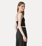 Woman wearing a black sleeveless top and black pants on a white background