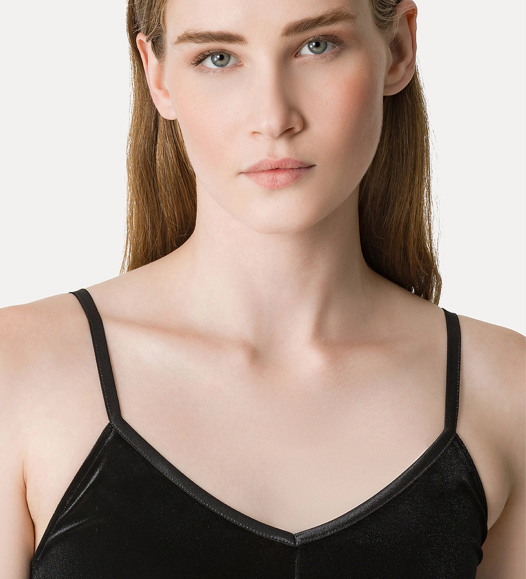 Woman wearing a black velvet top against a plain background