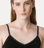 Woman wearing a black velvet top against a plain background
