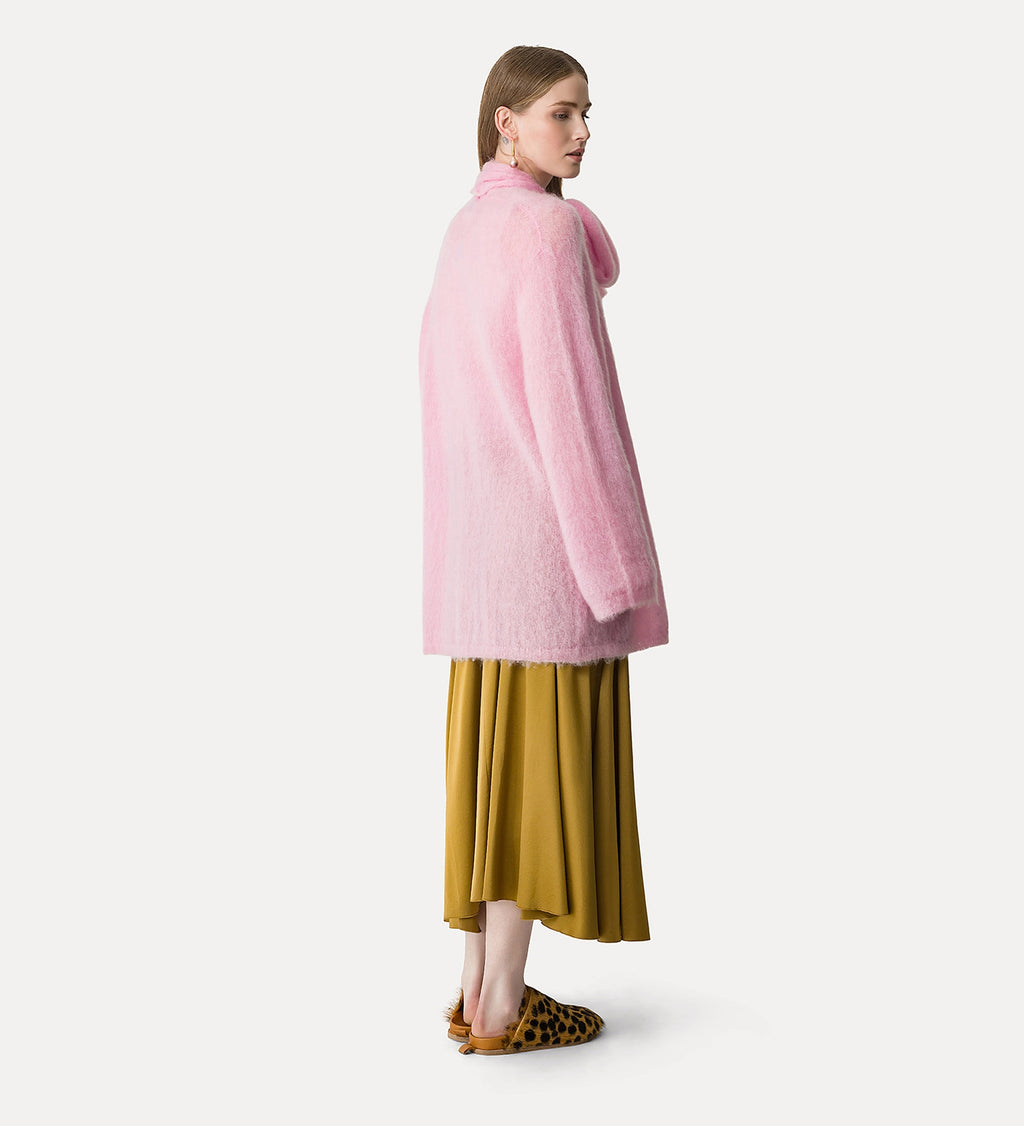 Woman wearing a pink coat and mustard skirt on a white background