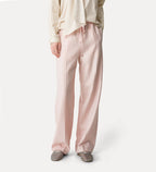 Person wearing light pink satin pants on a white background