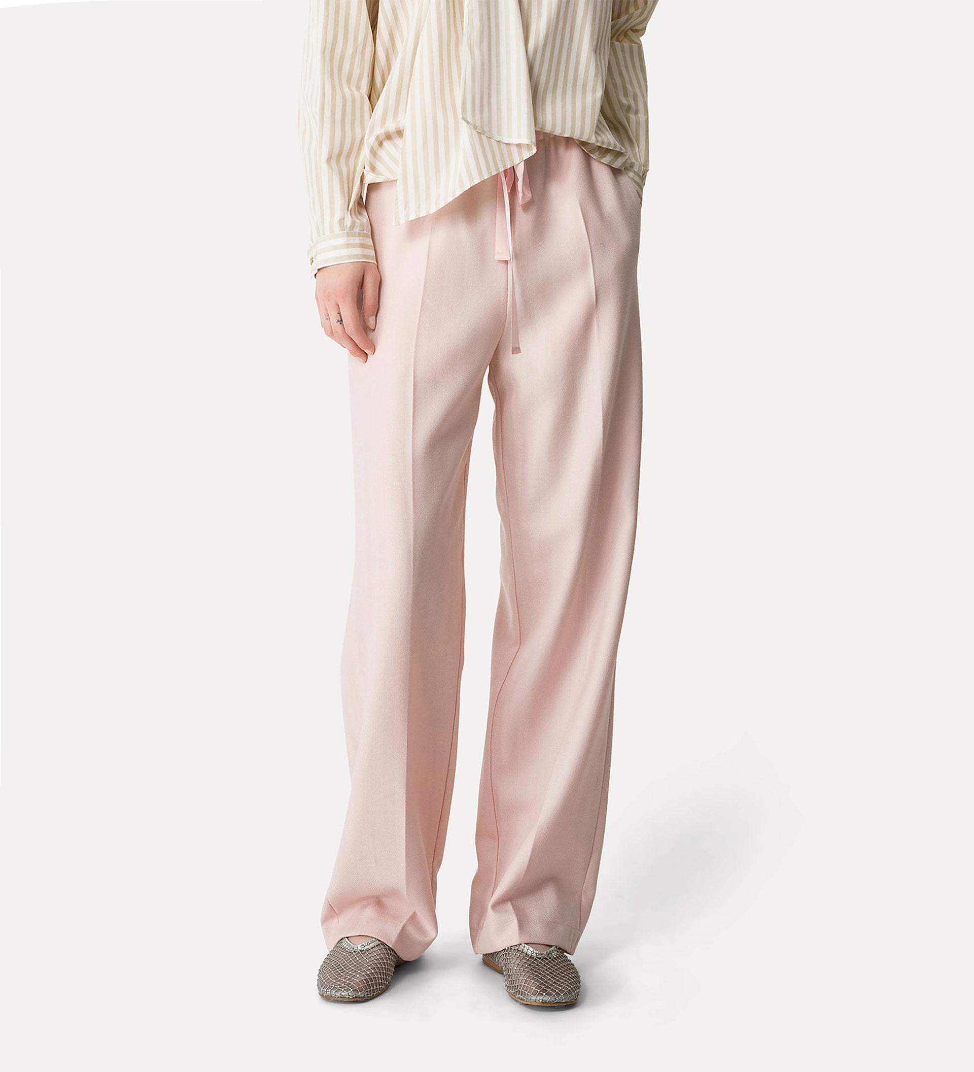 Person wearing light pink satin pants on a white background