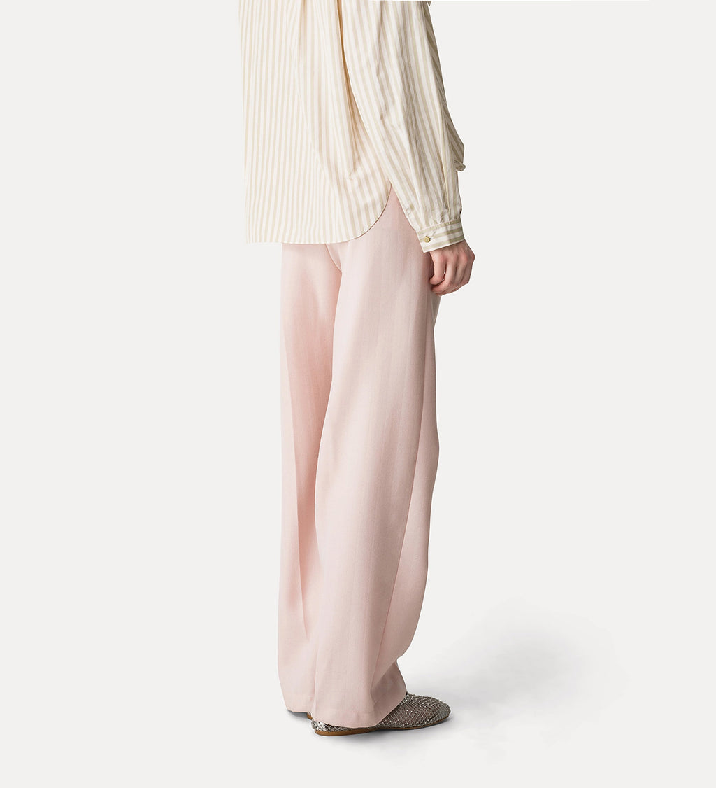 Person wearing a light-colored striped shirt and pink pants on a white background