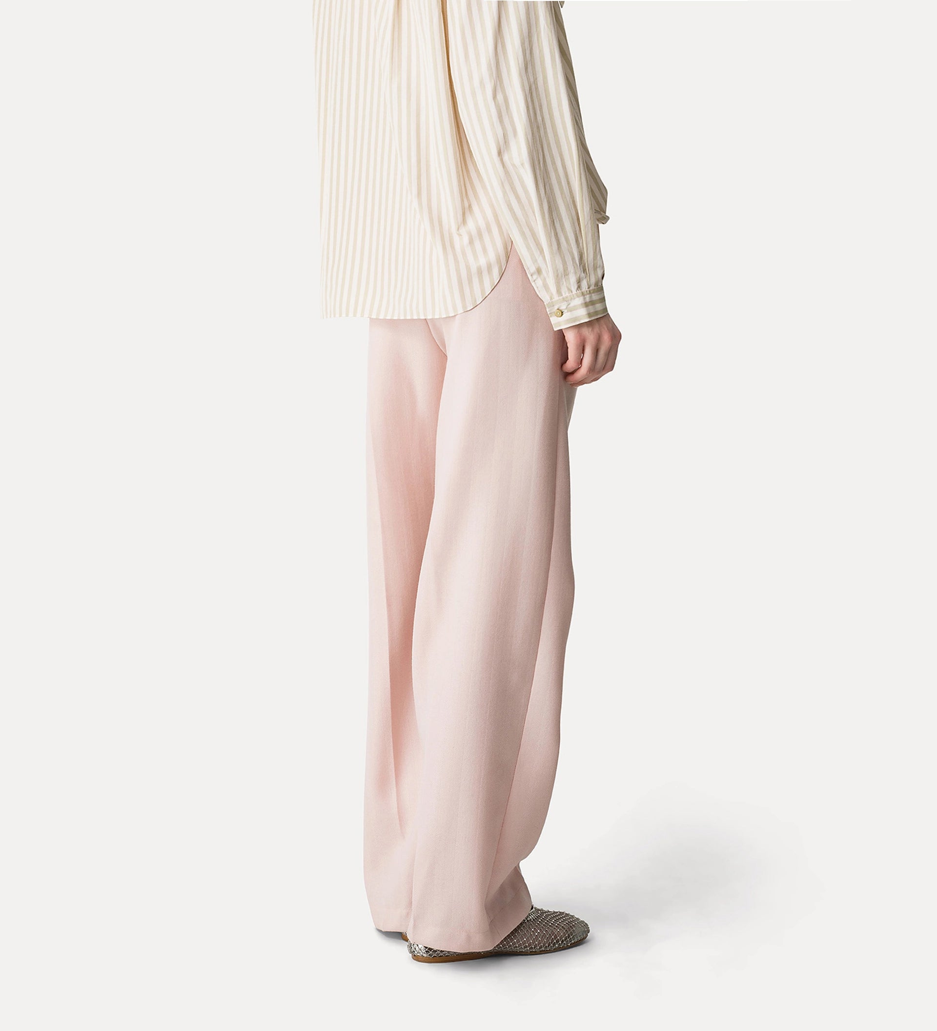 Person wearing a light-colored striped shirt and pink pants on a white background