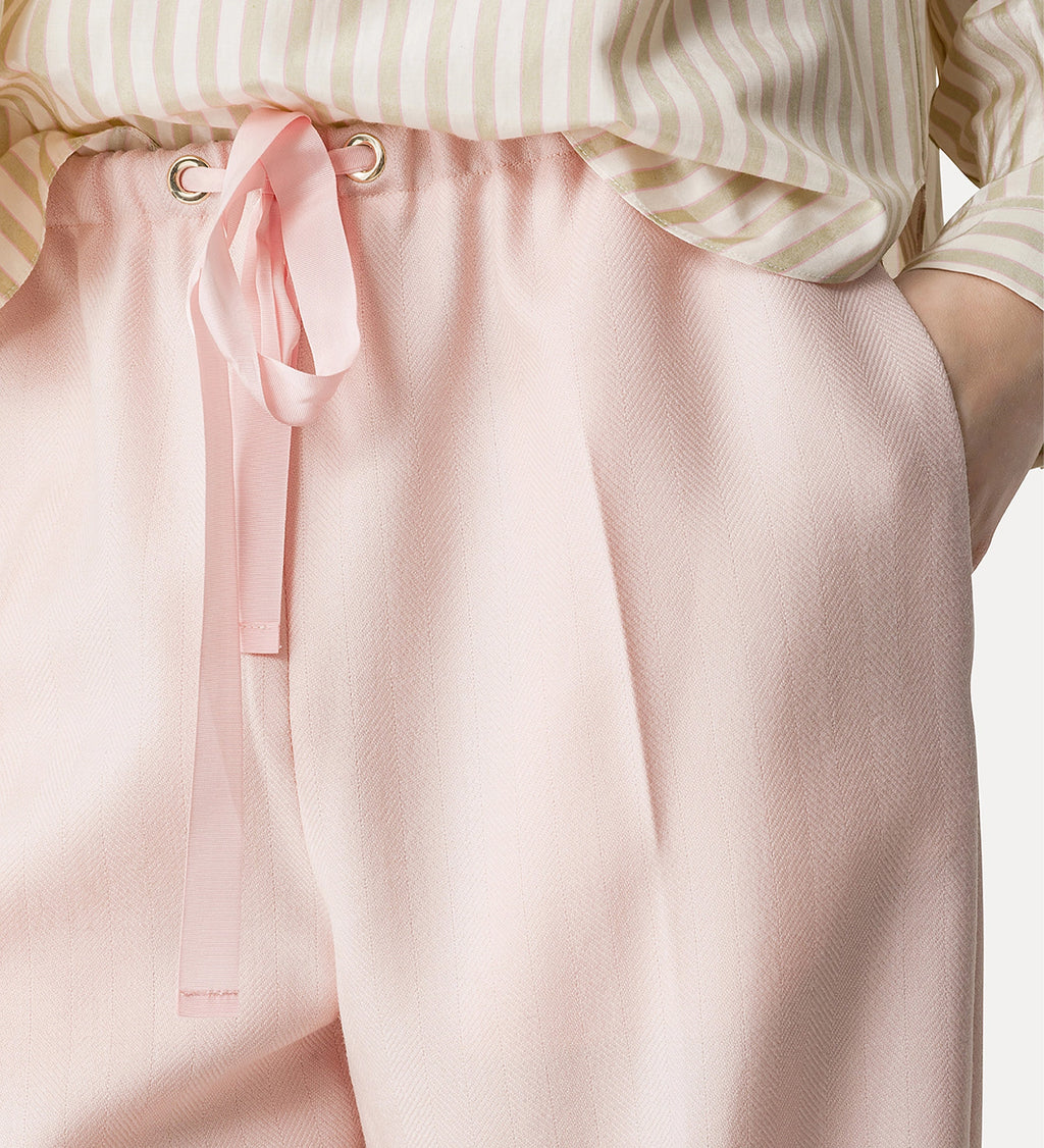 Light pink pants with a bow detail on a white background