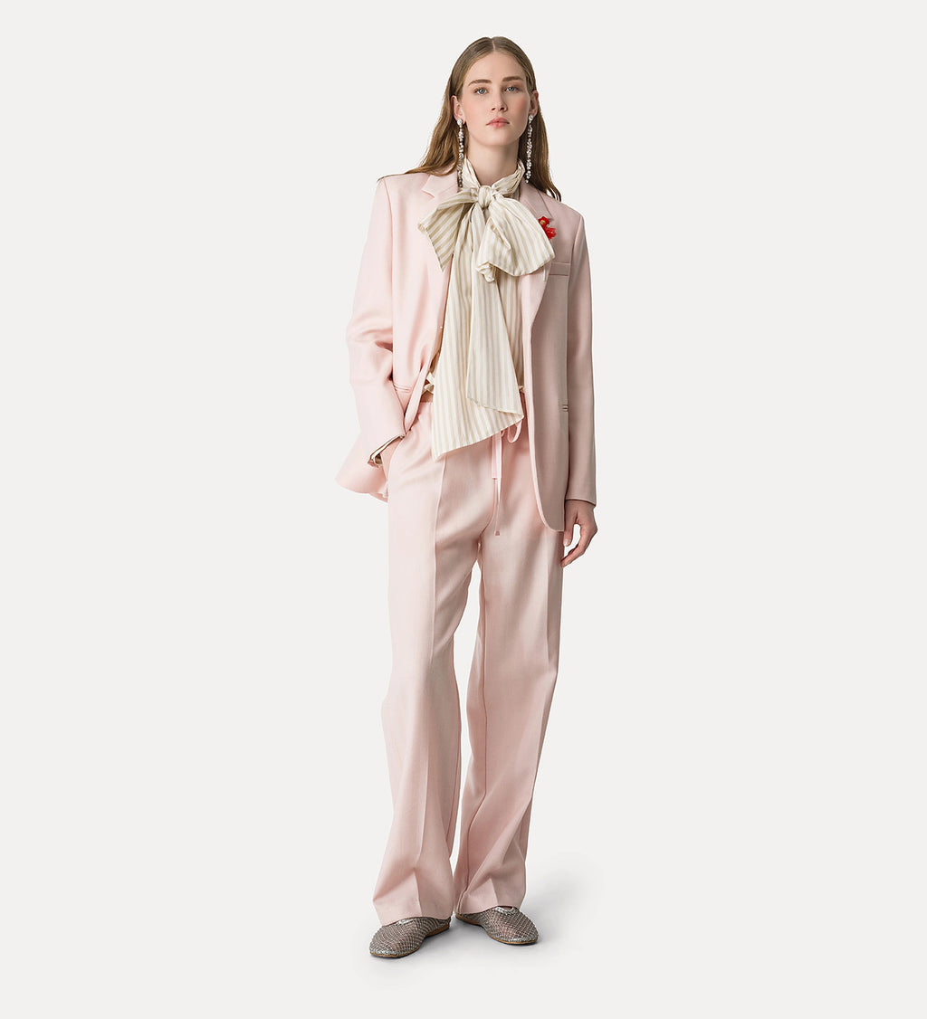 Woman wearing a light pink outfit with a bow tie on a white background