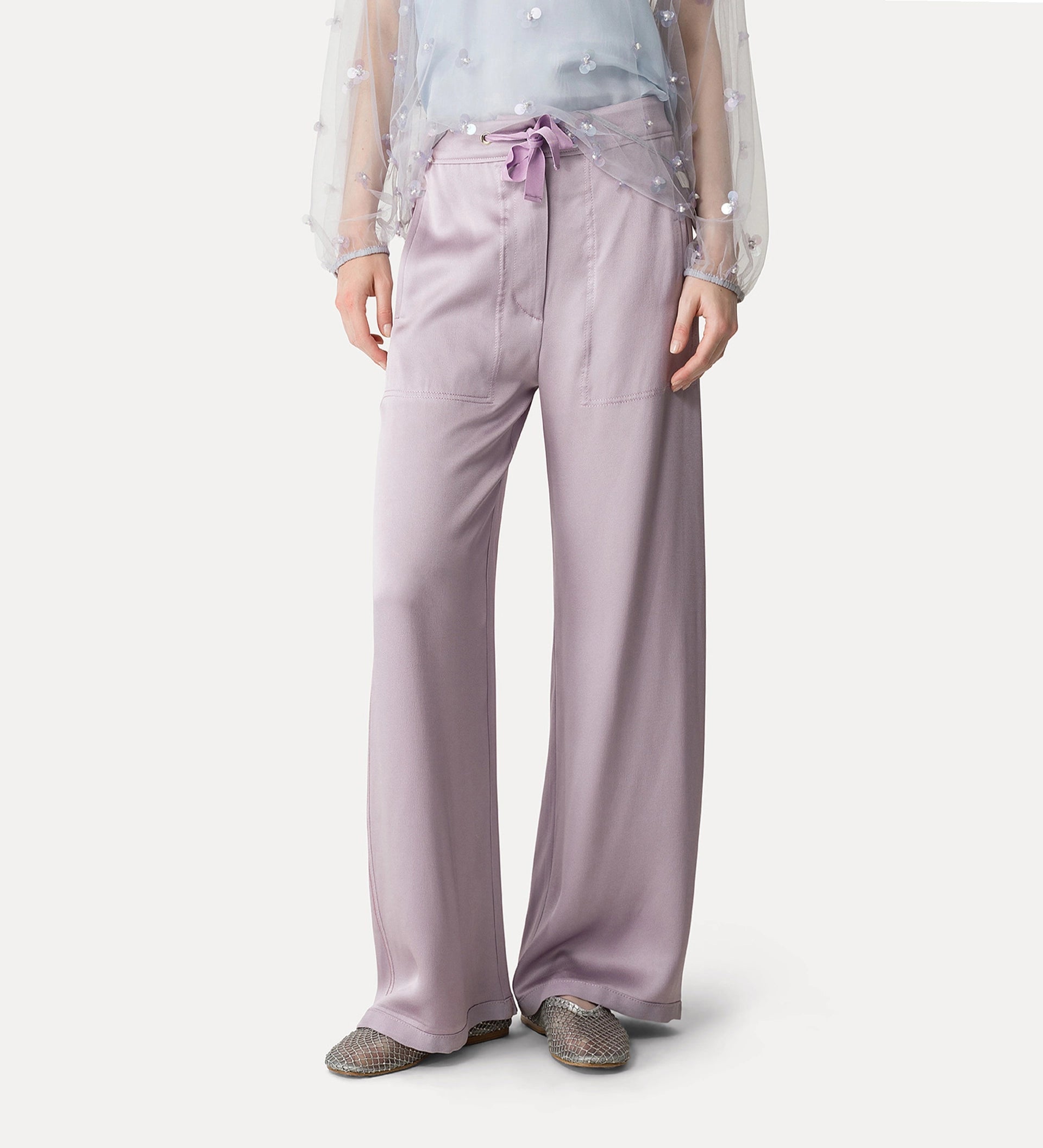 Person wearing light purple satin pants on a white background