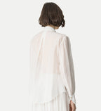 Person wearing a white blouse with a plain background
