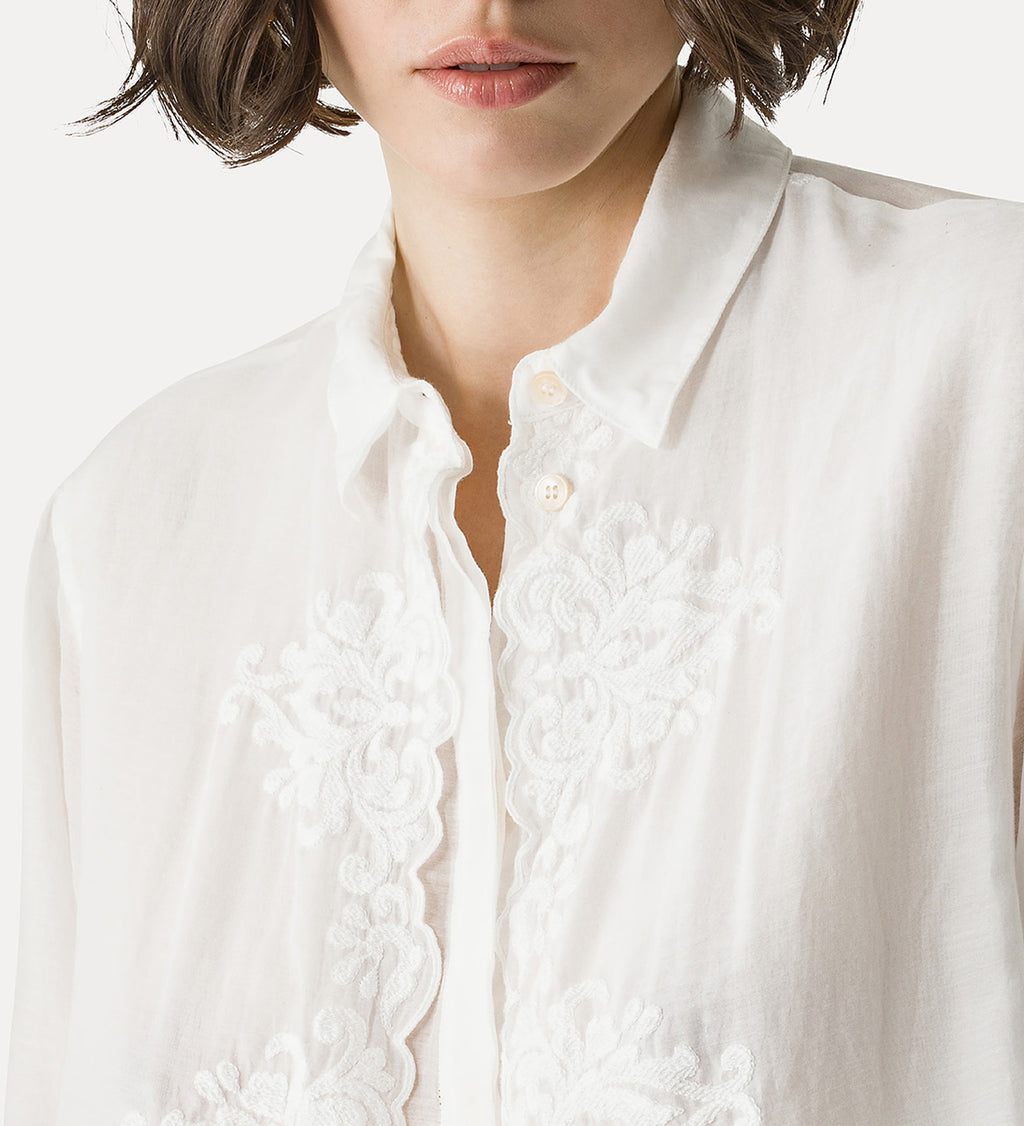 Close-up of a white blouse with lace details on a plain background