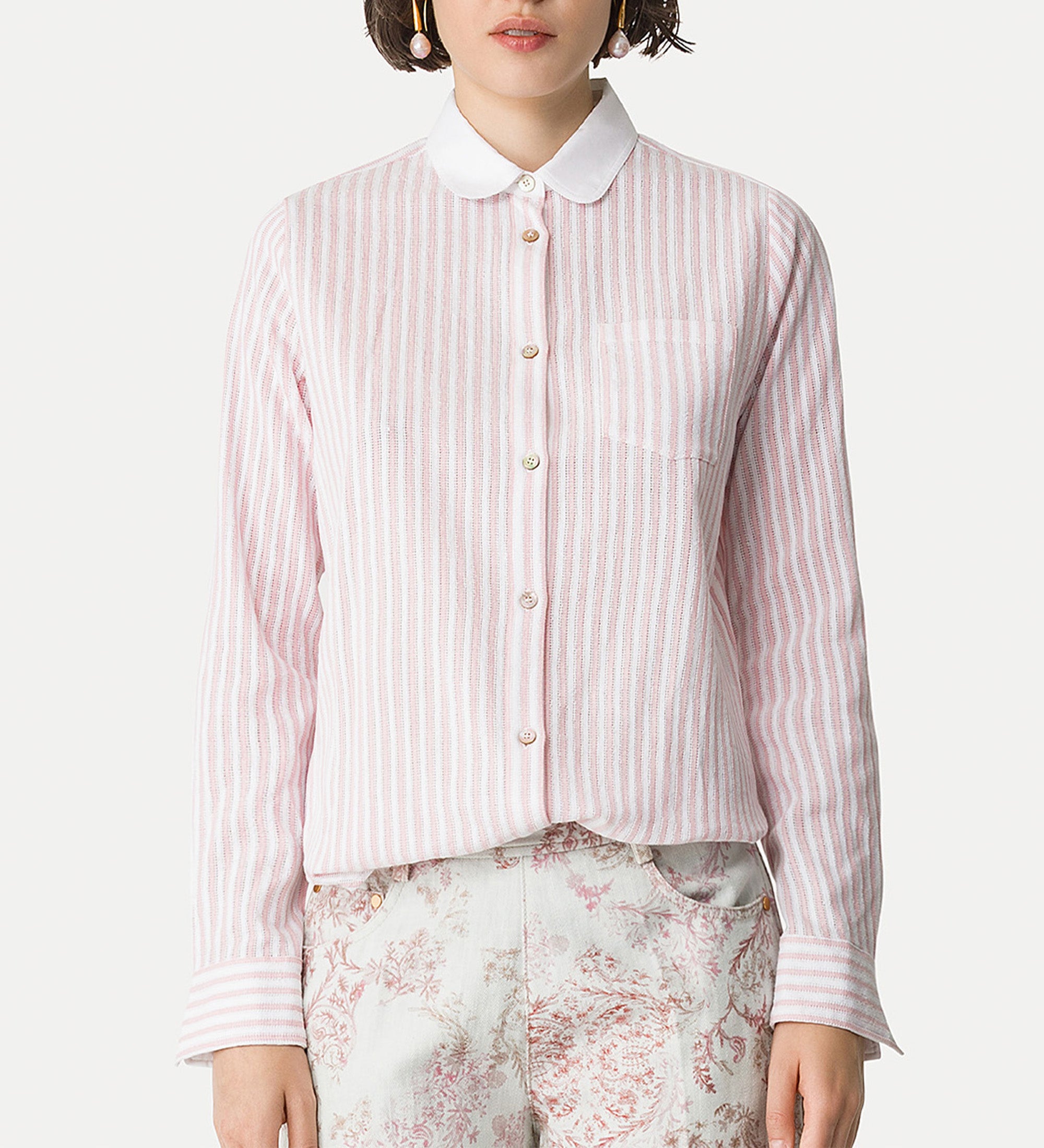 Person wearing a pink and white striped shirt with a white collar on a white background