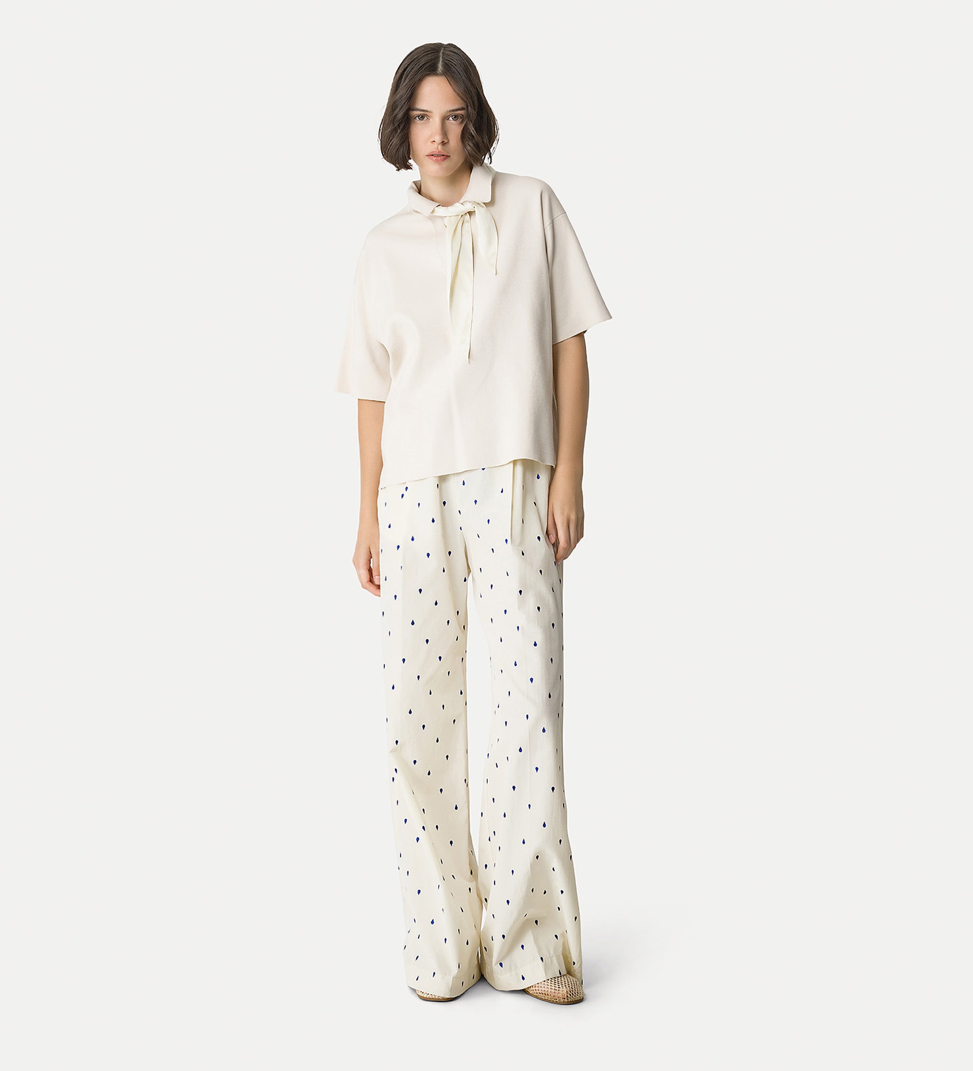 Woman wearing a white blouse and polka dot pants on a white background