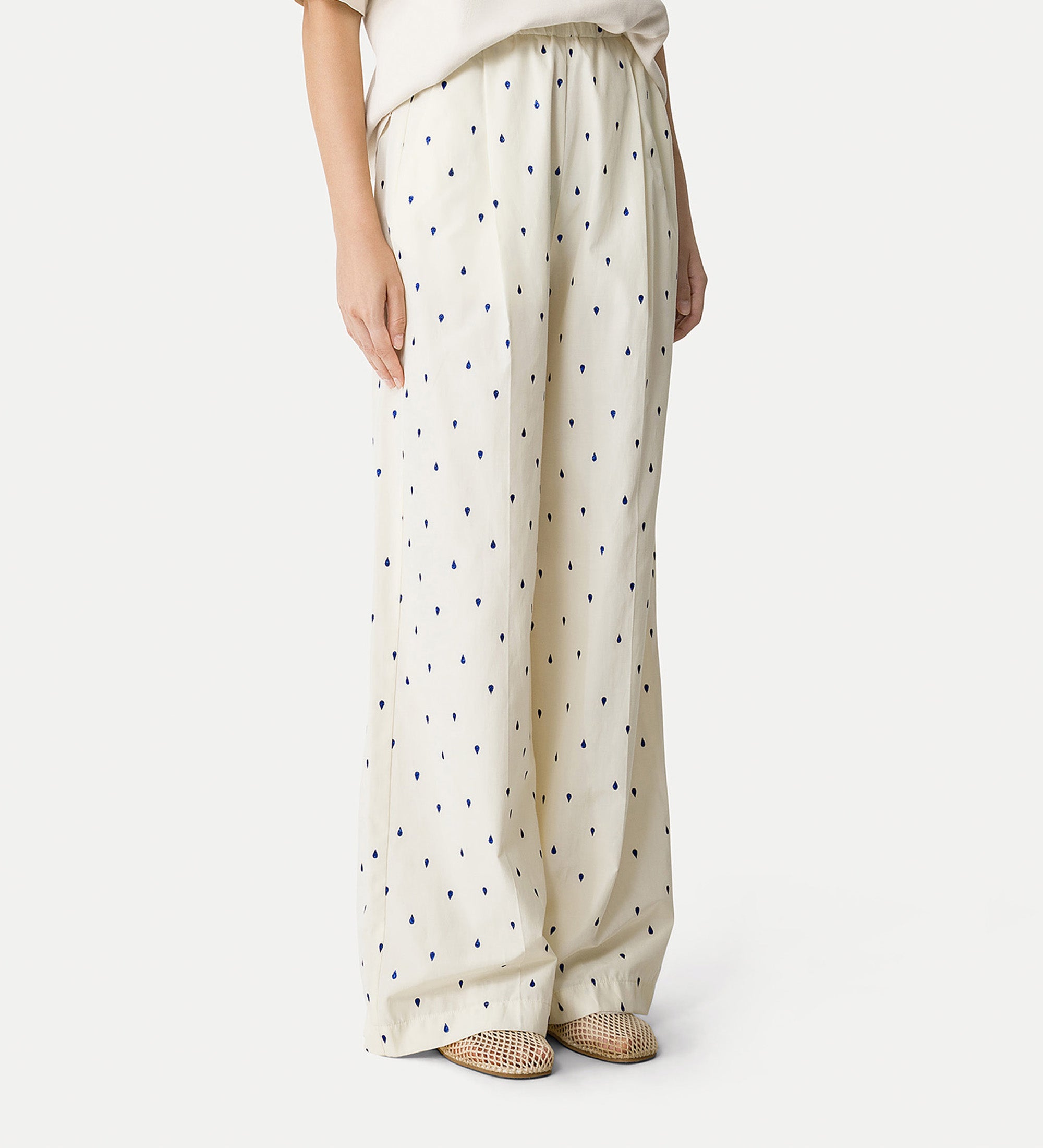 White pants with black polka dots worn by a person on a white background