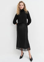 Woman wearing a black outfit with a lace hem on a white background