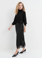 Woman wearing a black outfit with a lace hem on a white background