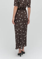 Woman wearing a brown dress with white polka dots on a light gray background