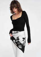 Woman wearing a black one-shoulder top and a black and white patterned skirt on a white background