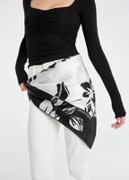 Person wearing a black and white patterned scarf with a plain background
