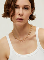 Woman wearing a delicate necklace against a plain background