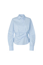 A light blue long-sleeve button-up shirt with a pointed collar and a unique gathered front detail, displayed on a clean white background.