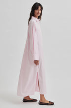 Woman wearing a long light pink shirt with a white background